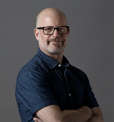 Speaker Aaron Balick standing with his arms folded
