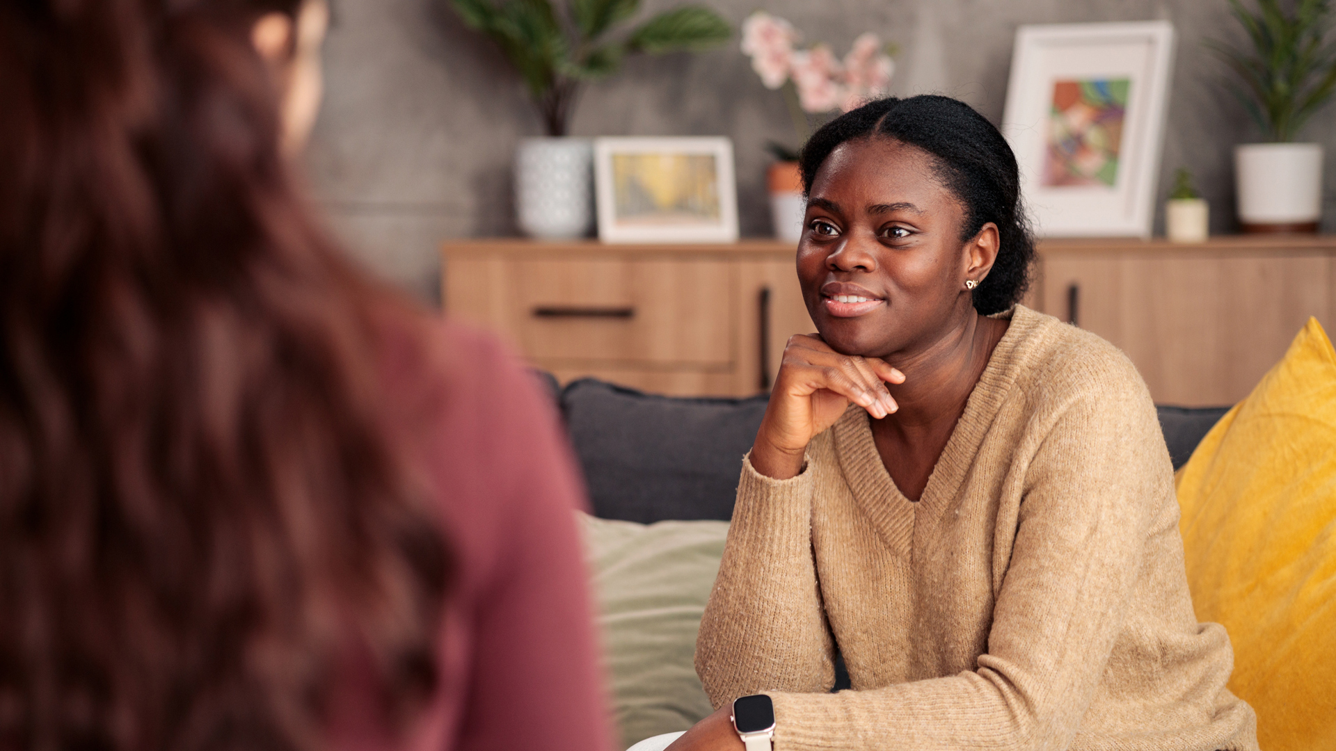 Woman sitting with hand under chin listening to another women sitting across from her