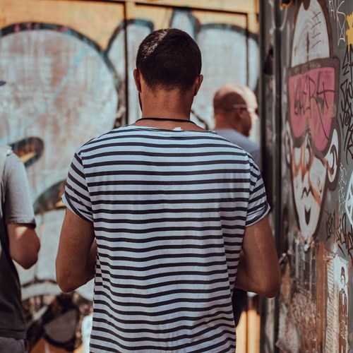 Men exploring streets next to walls with urban art