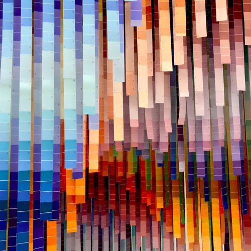 An artistic installation of multiple colours on long strips hanging from the ceiling. 