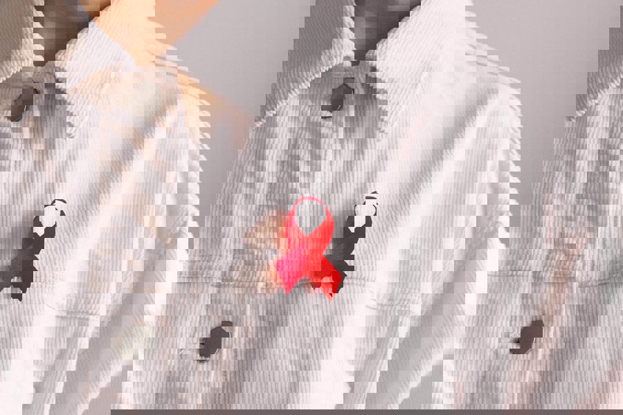 Person with white shirt wearing the red ribbon symbolising awareness and support for people living with HIV.